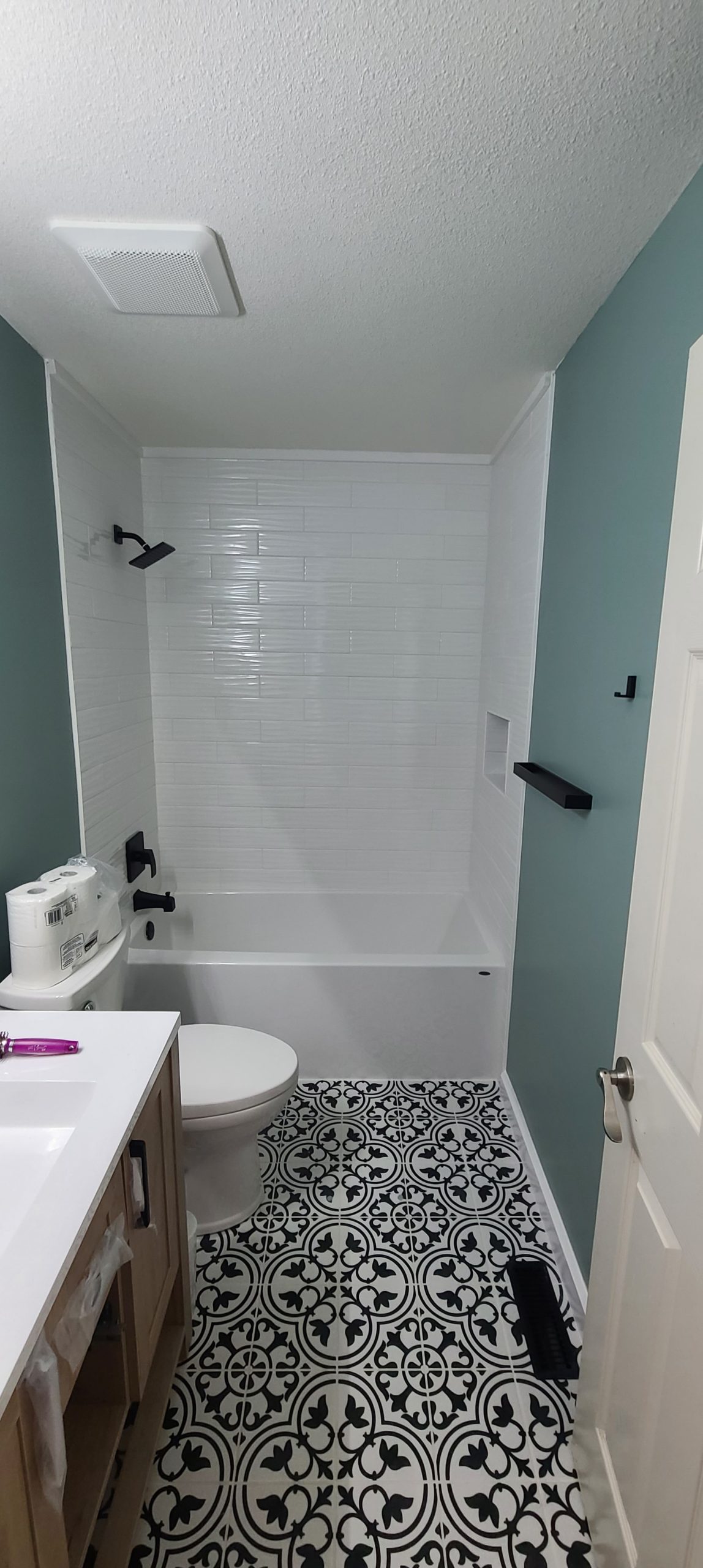 Completed bathroom with mint walls, white tub, patterned floor, and wood vanity